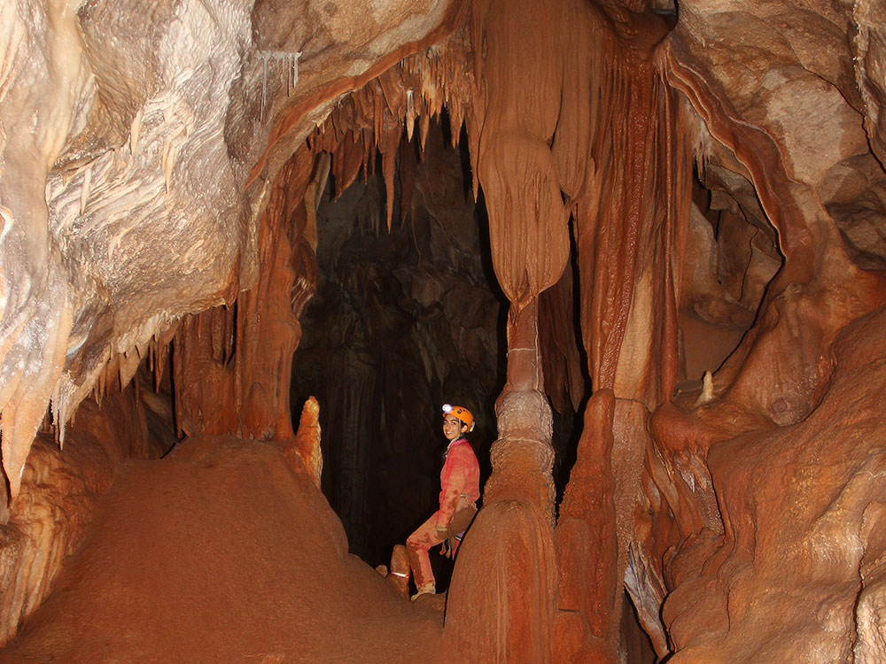 jeune homme fait de la spéléologie dans une grotte